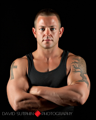 Fitness portrait shot in the studio using dramatic side lighting to emphasize his muscle contours.